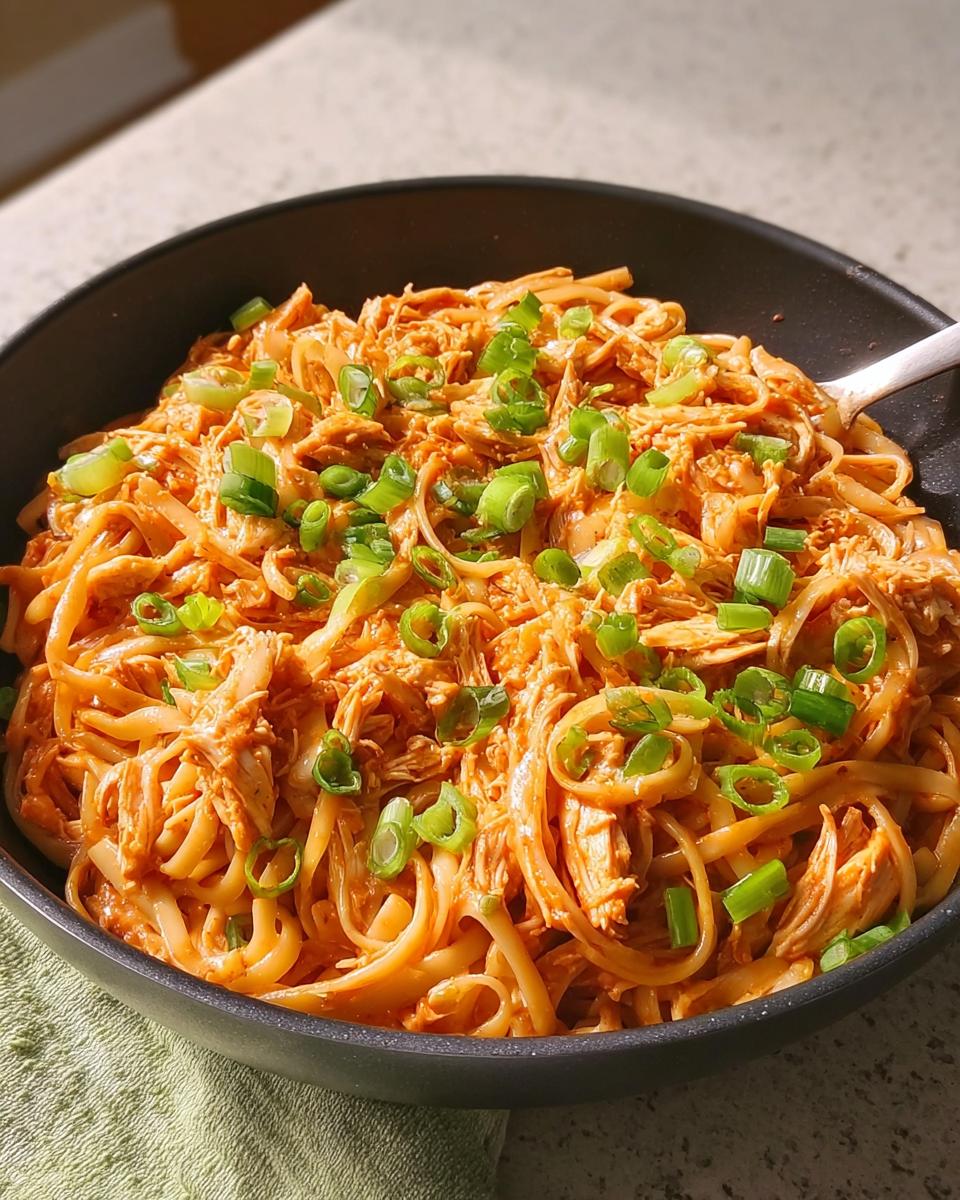 A close-up of a bowl filled with creamy chicken noodles, garnished with chopped green onions. A perfect example of 5-Ingredient Dinner Ideas.