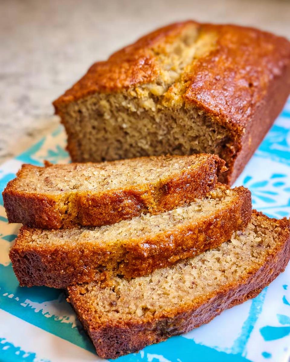 Three thick slices of moist Banana Bread with Sour Cream resting in front of the loaf.