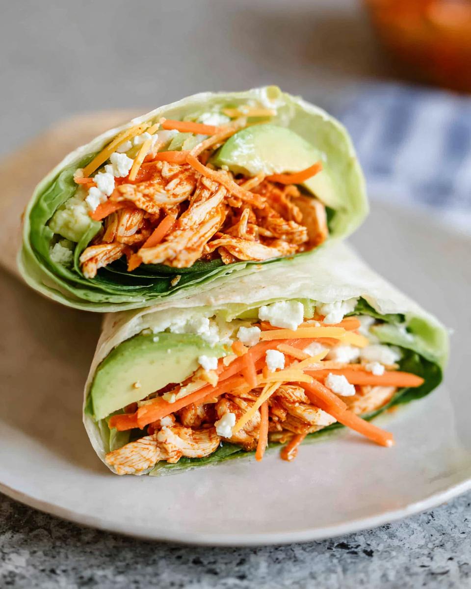 Close-up of Buffalo Chicken Lettuce Wraps filled with shredded chicken, avocado, shredded carrots, cheese, and crumbled feta.