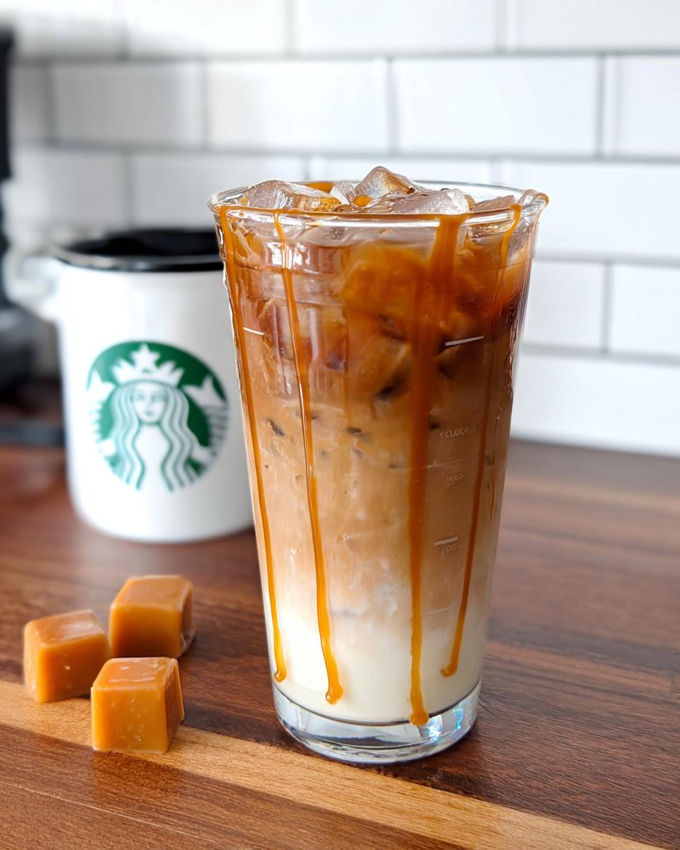 A tall glass of layered Café-Style Iced Caramel Macchiato copycat drink with caramel drizzle, next to caramel squares.