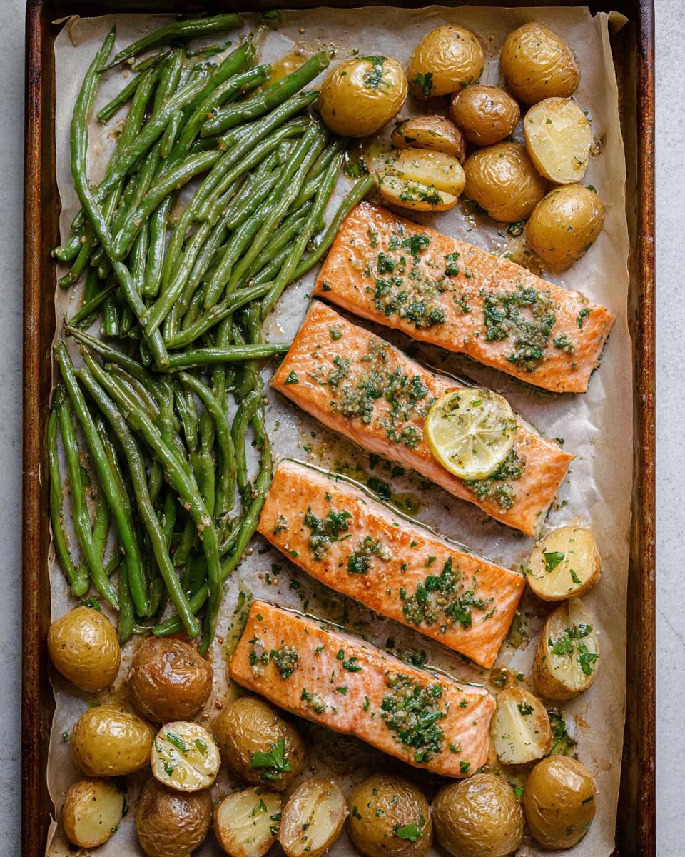 Overhead view of Sheet-Pan Salmon & Veggies with salmon fillets, roasted potatoes, and green beans on a baking sheet.