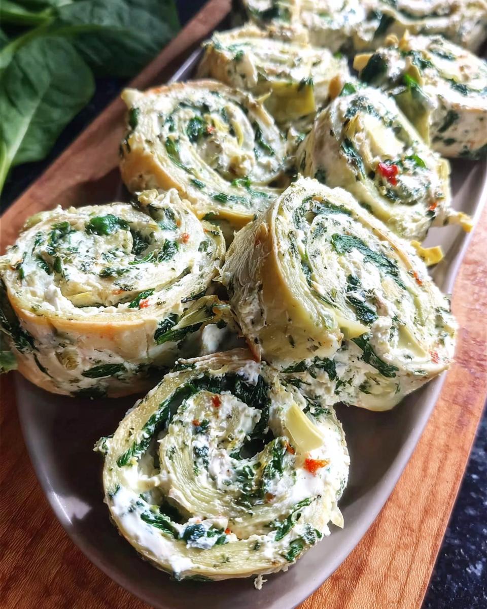 Close-up of several sliced Spinach Dip Pinwheels showing the creamy filling with spinach and artichoke.