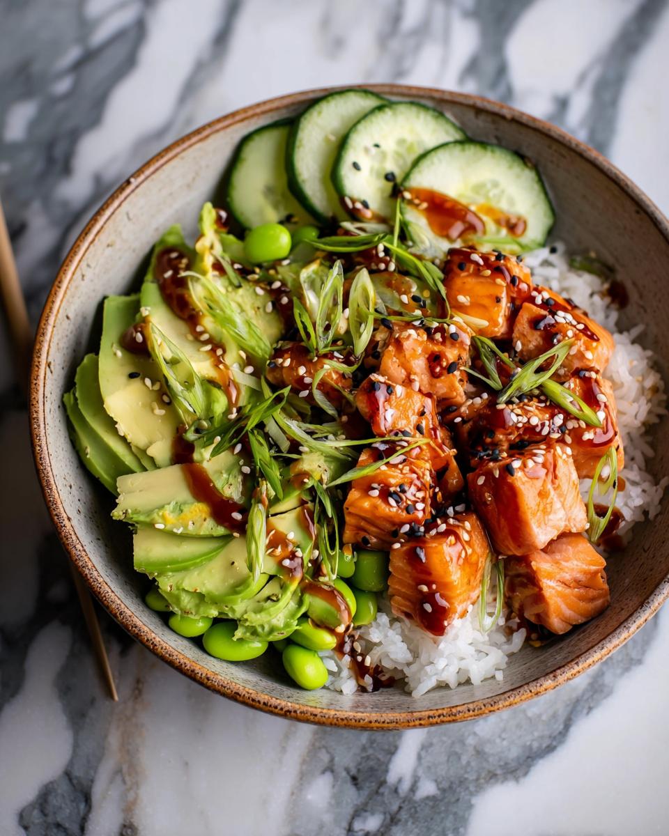 A vibrant bowl featuring teriyaki salmon cubes over rice, topped with sliced avocado, cucumbers, and sesame seeds.