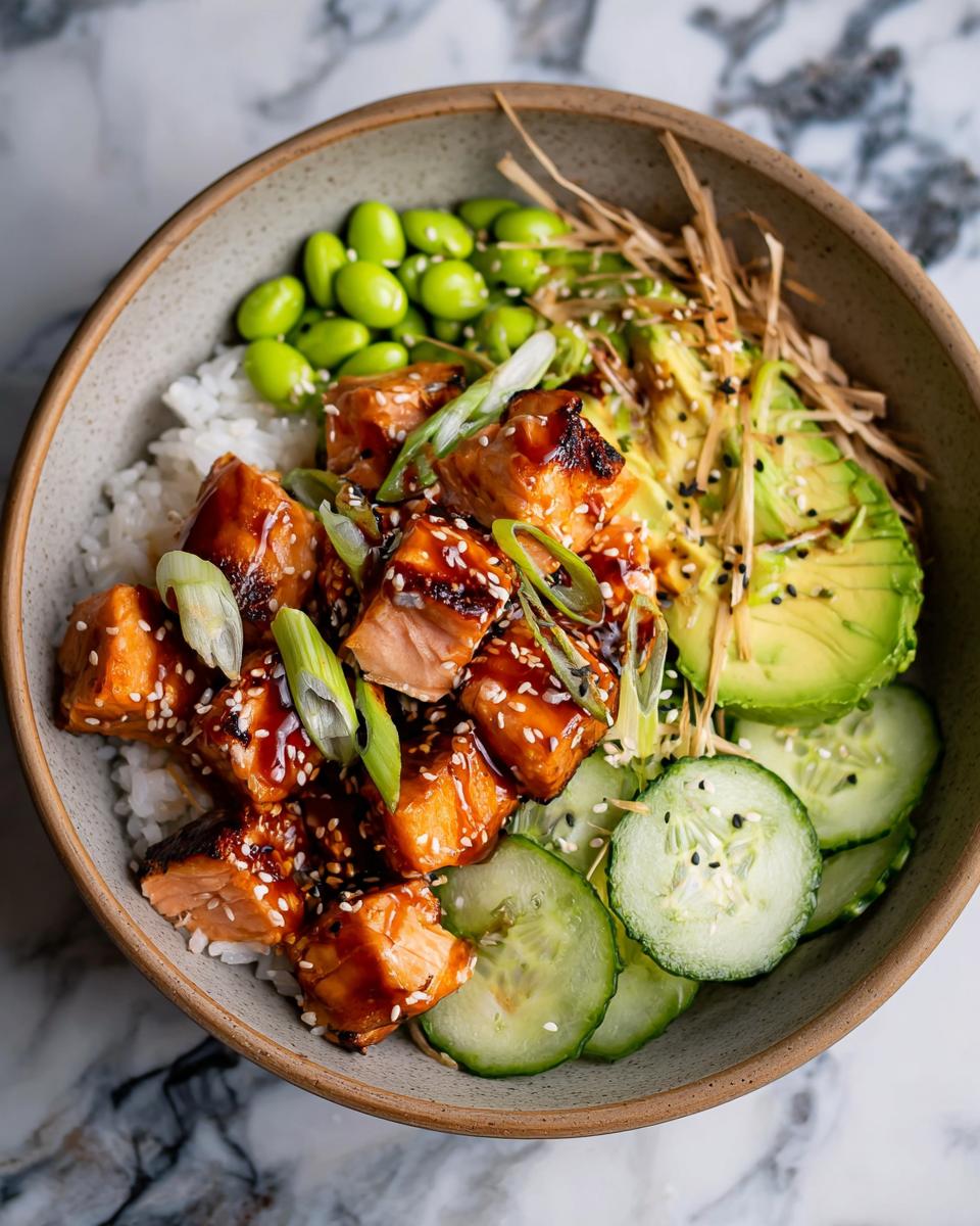Close-up of a Teriyaki Salmon Bowls featuring glazed salmon cubes over rice with edamame, avocado, and cucumber.