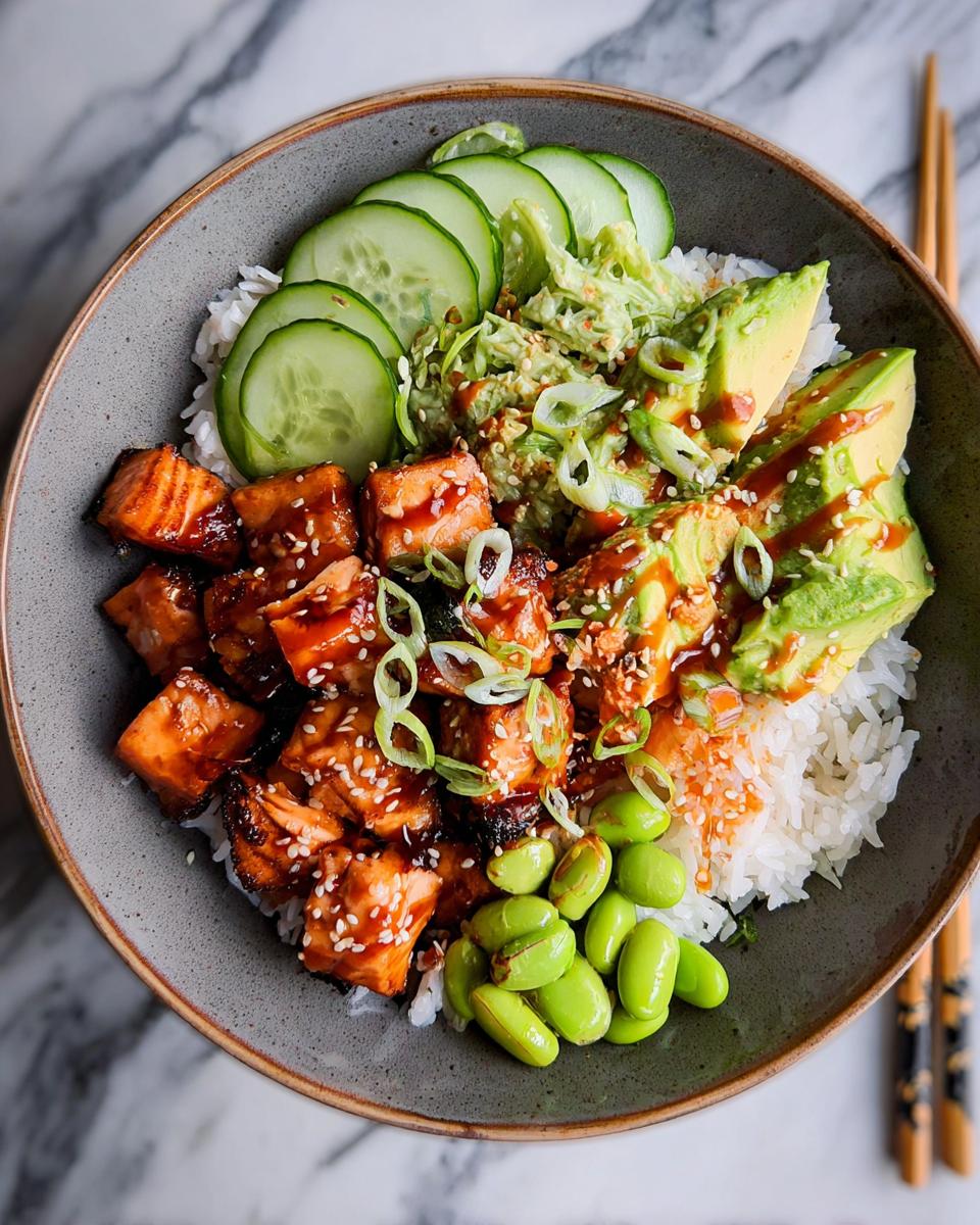 Overhead view of a Teriyaki Salmon Bowls featuring glazed salmon chunks, rice, avocado, cucumber, and edamame.