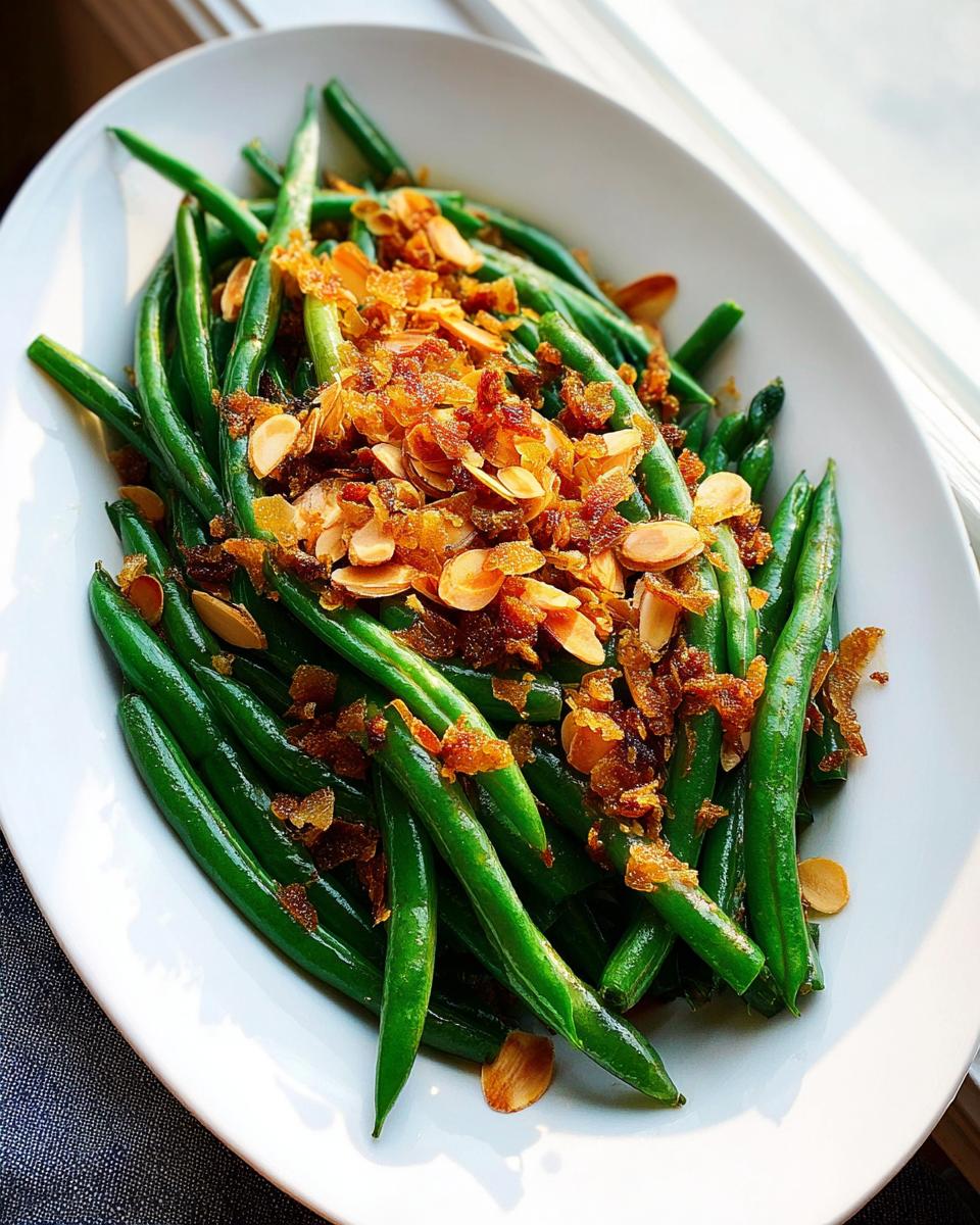 Close-up of vibrant green beans topped with crispy fried onions and sliced almonds, perfect for Thanksgiving.