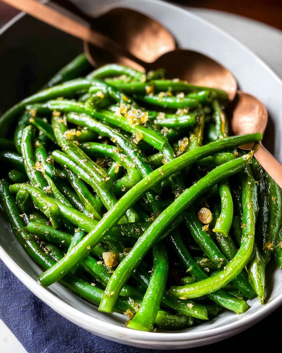 Close-up of bright green Thanksgiving green beans tossed with garlic and seasoning in a serving bowl.