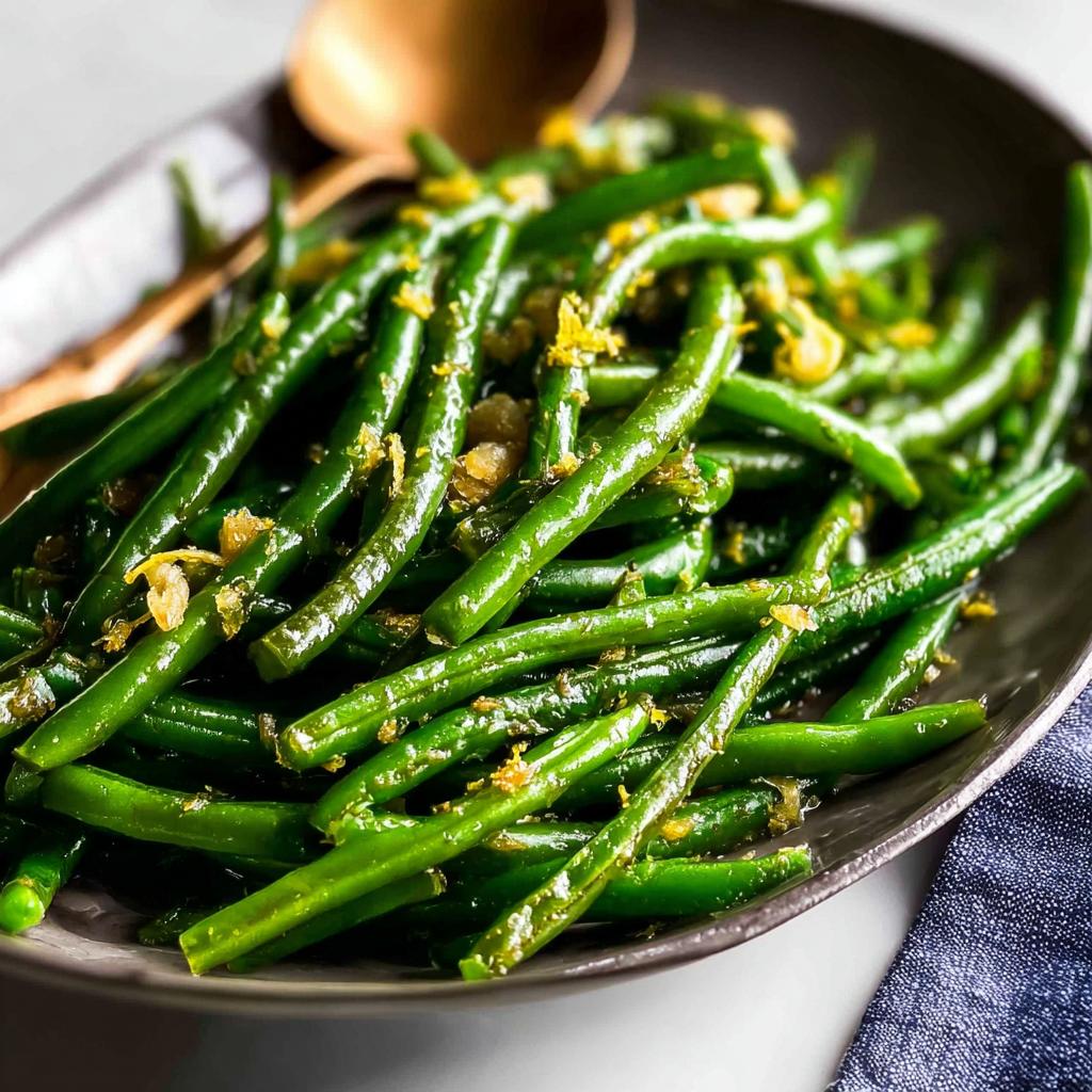 A close-up of glistening, perfectly cooked Thanksgiving green beans with lemon zest and garlic.