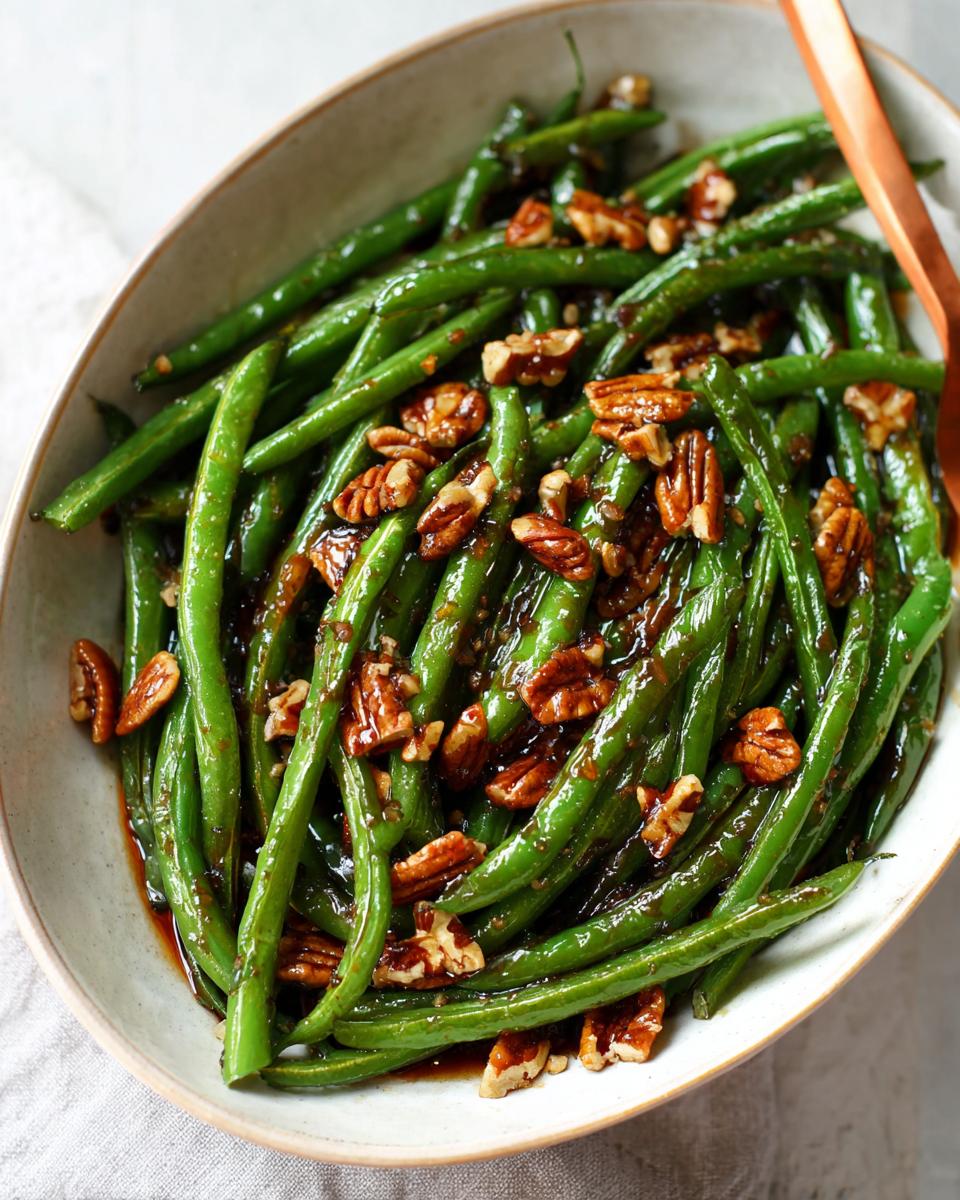 Close-up of Thanksgiving Green Beans for Busy Weeknights, glazed and topped with toasted pecans in a serving dish.