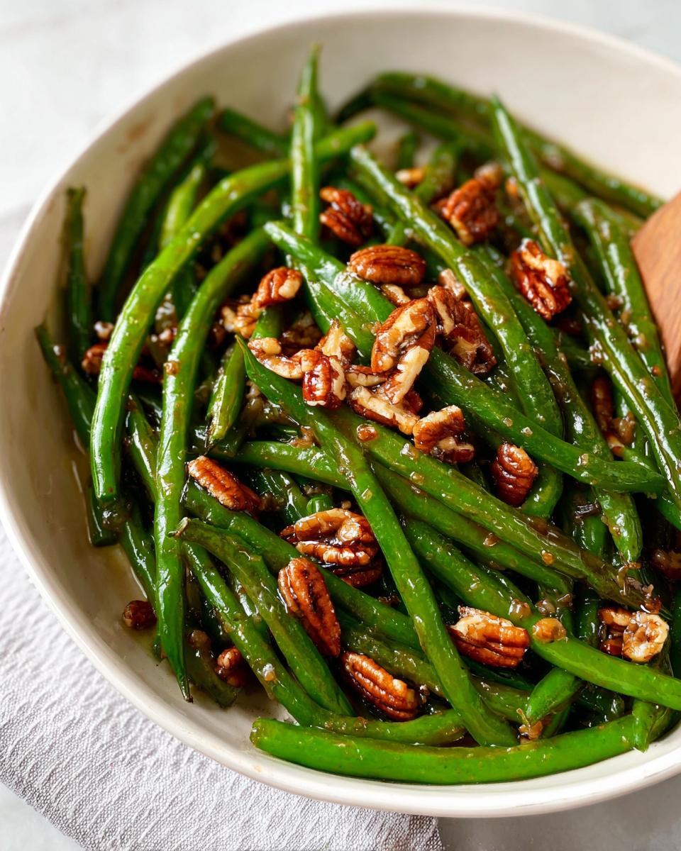 Close-up of a bowl filled with vibrant green beans topped with toasted pecans, part of a Thanksgiving Green Beans Recipe.