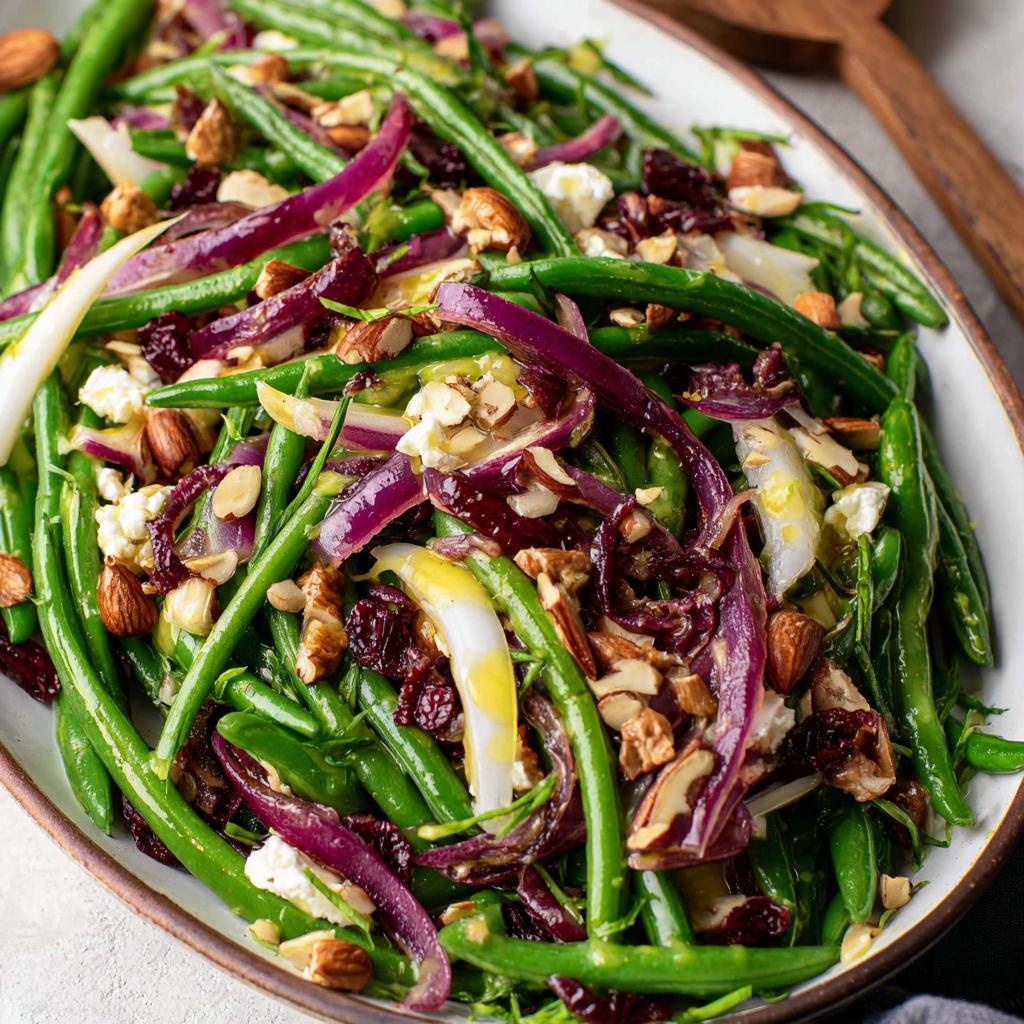A vibrant Thanksgiving salad featuring fresh green beans, red onion, dried cranberries, almonds, and feta cheese.