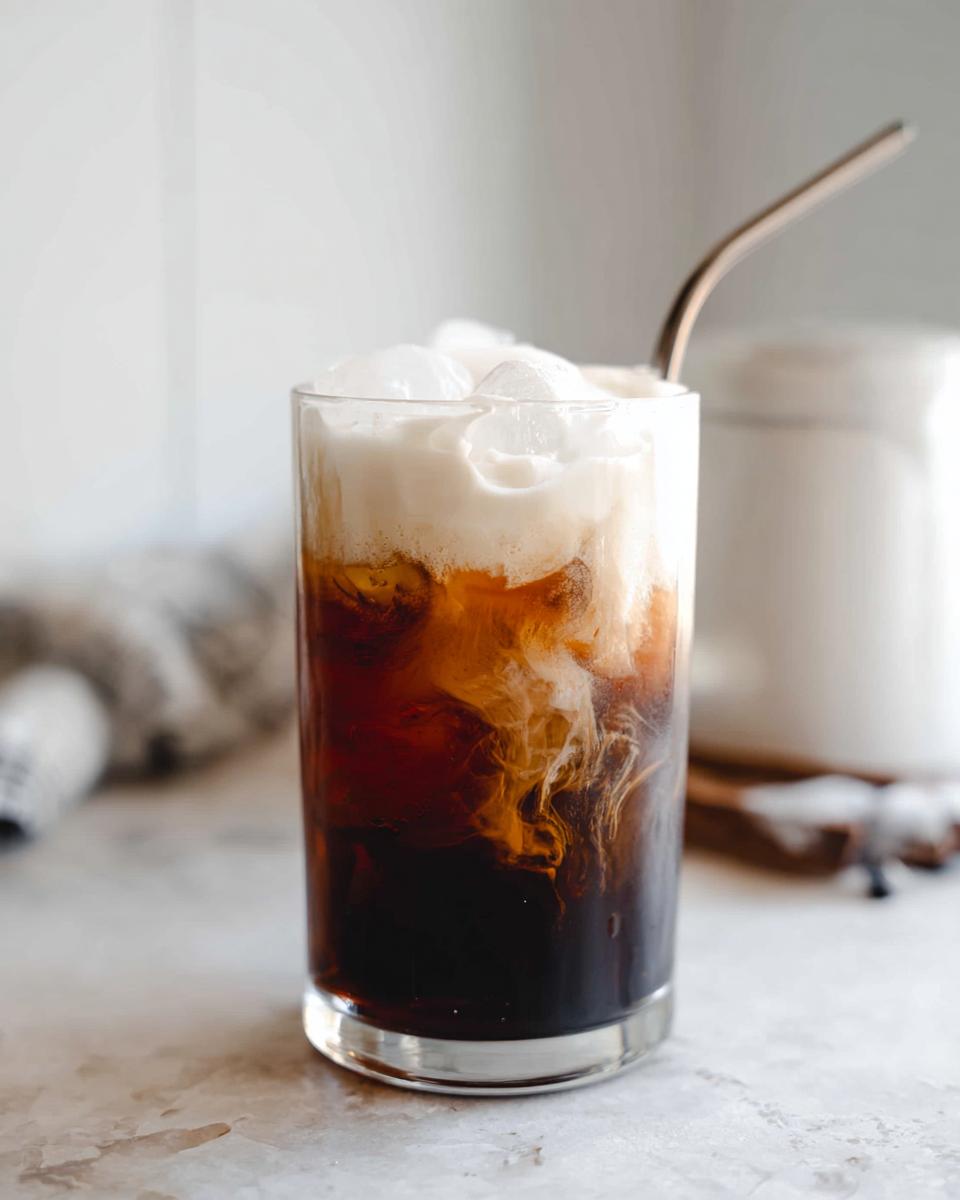 A tall glass of Vanilla Sweet Cream Cold Foam Cold Brew with ice and a metal straw.