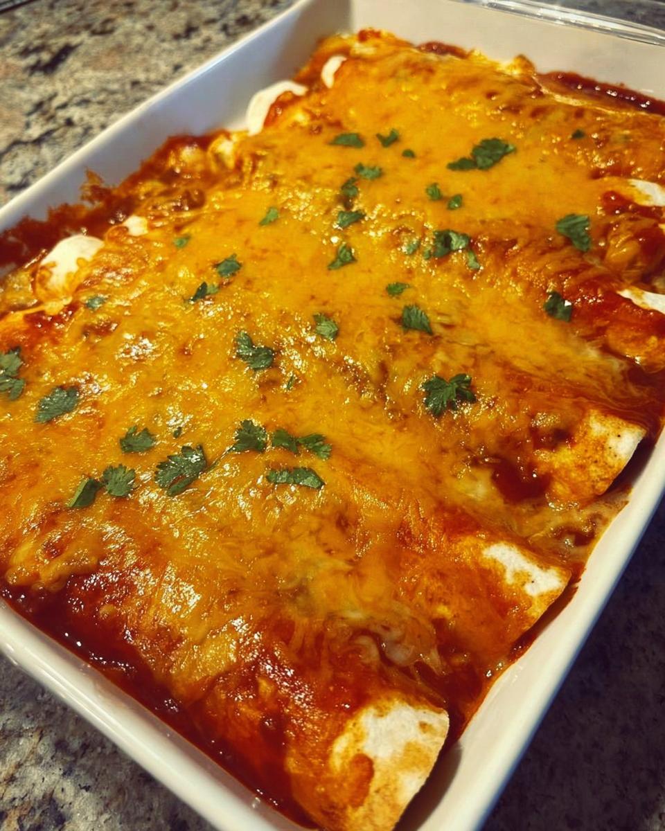 Close-up of freshly Baked Cheesy Beef Enchiladas covered in melted orange cheese and garnished with cilantro.