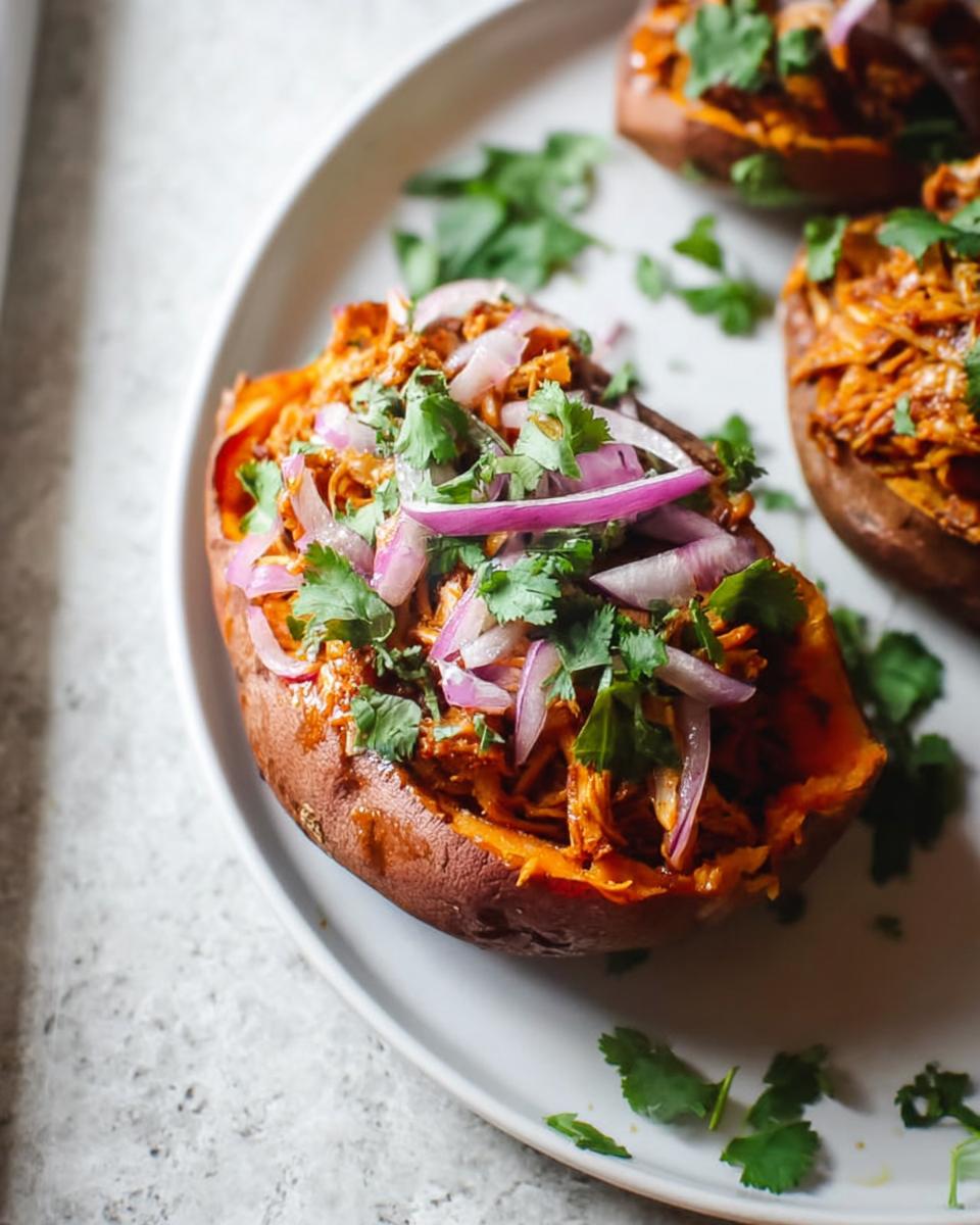 Close-up of BBQ Chicken Stuffed Sweet Potatoes topped with sliced red onion and fresh cilantro.