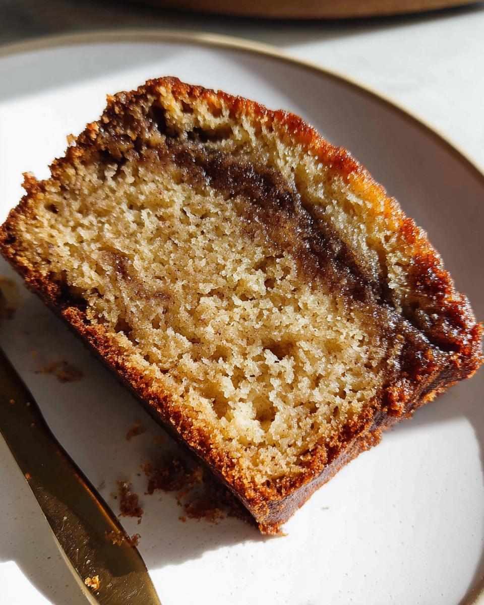 A close-up view of a moist slice of Cinnamon Swirl Banana Bread showing the rich, dark cinnamon swirl texture.