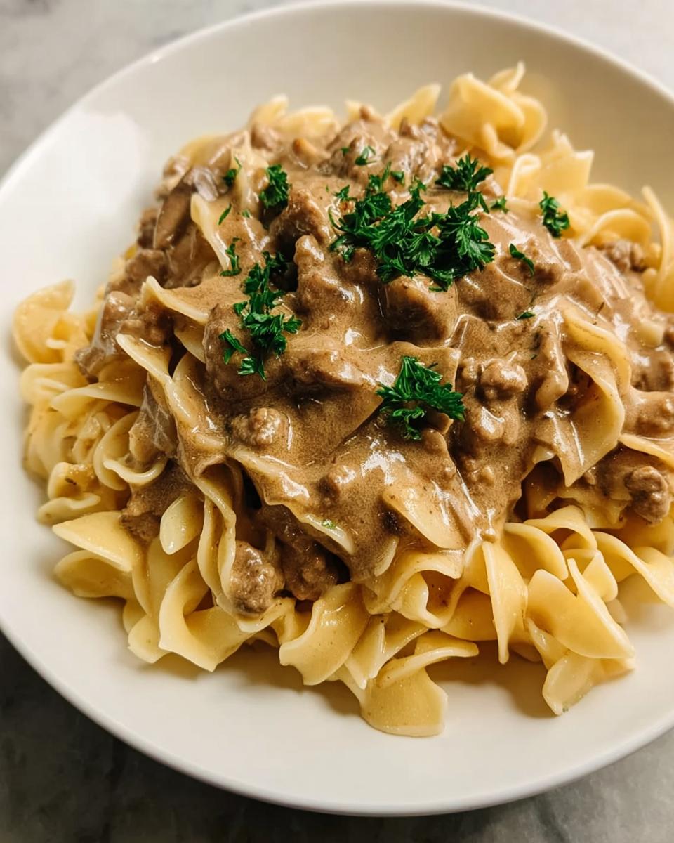 A close-up of Creamy Turkey Stroganoff served over wide egg noodles and garnished with fresh parsley.