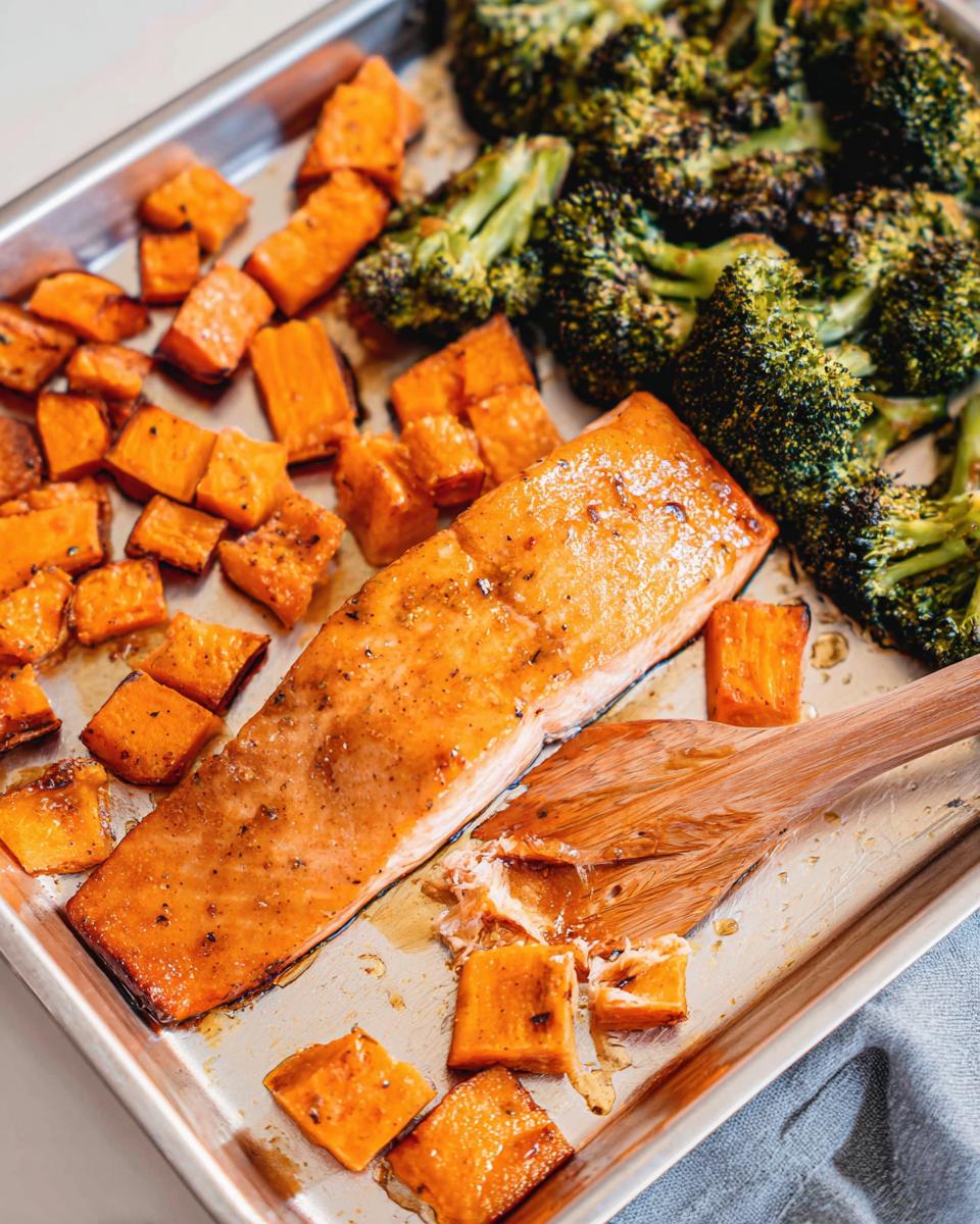 Close-up of a glistening Maple Dijon Salmon Sheet Pan Dinner with roasted sweet potatoes and broccoli florets.