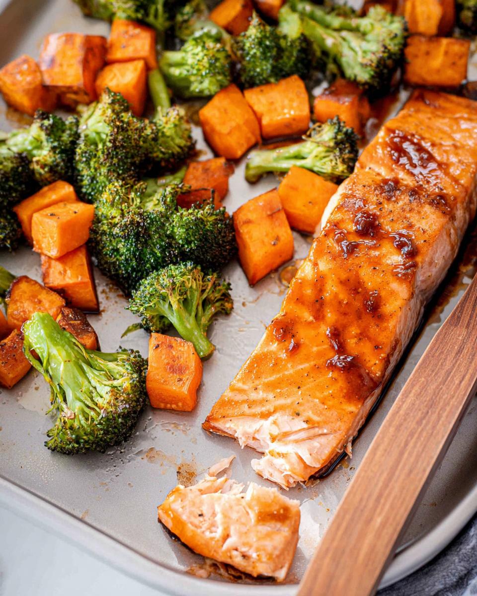 Close-up of a glazed salmon fillet next to roasted broccoli and sweet potatoes from the Maple Dijon Salmon Sheet Pan Dinner.
