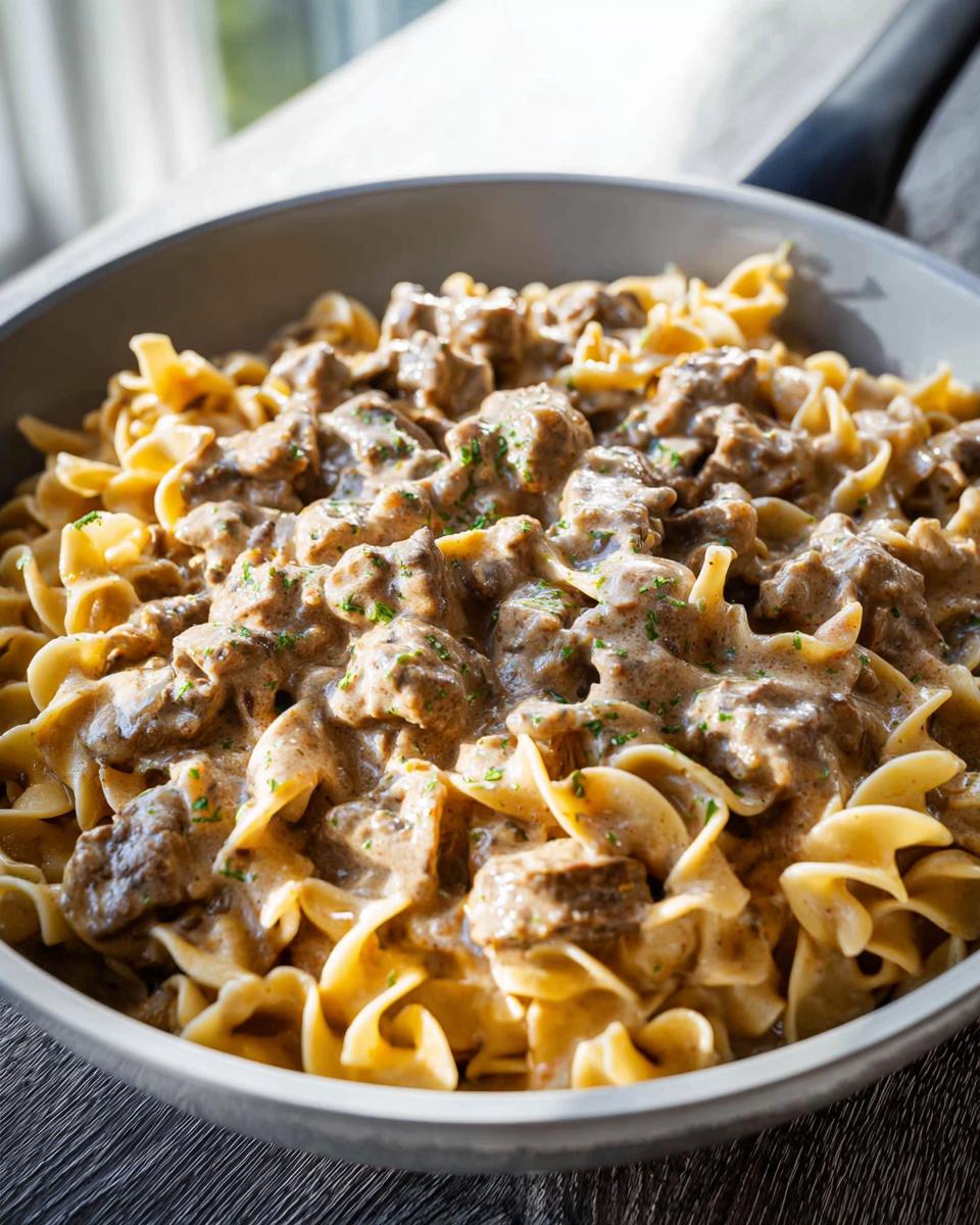 A close-up view of creamy One Pot Ground Beef Stroganoff served over wide egg noodles in a gray bowl.