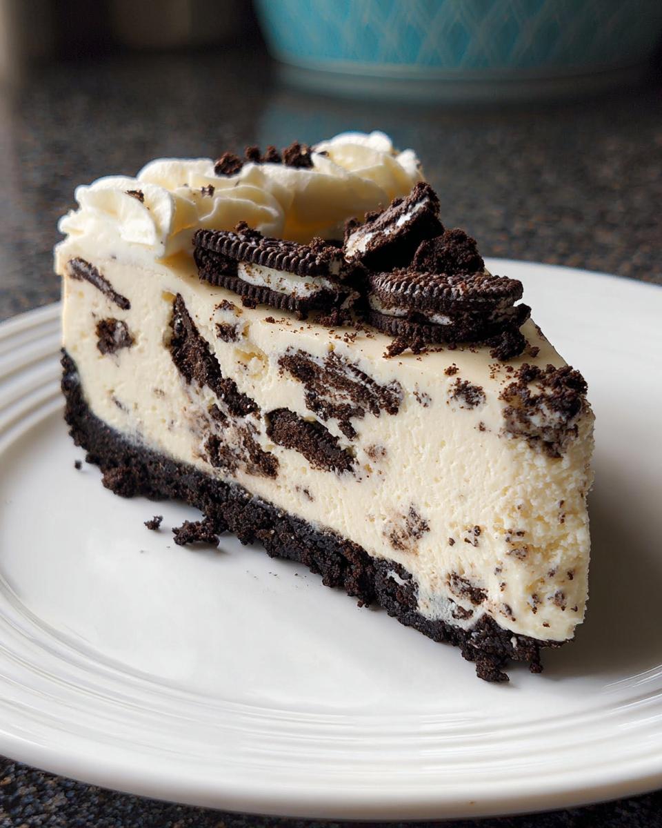 A perfect slice of Oreo Cookies and Cream Cheesecake with a dark crust and whipped topping.