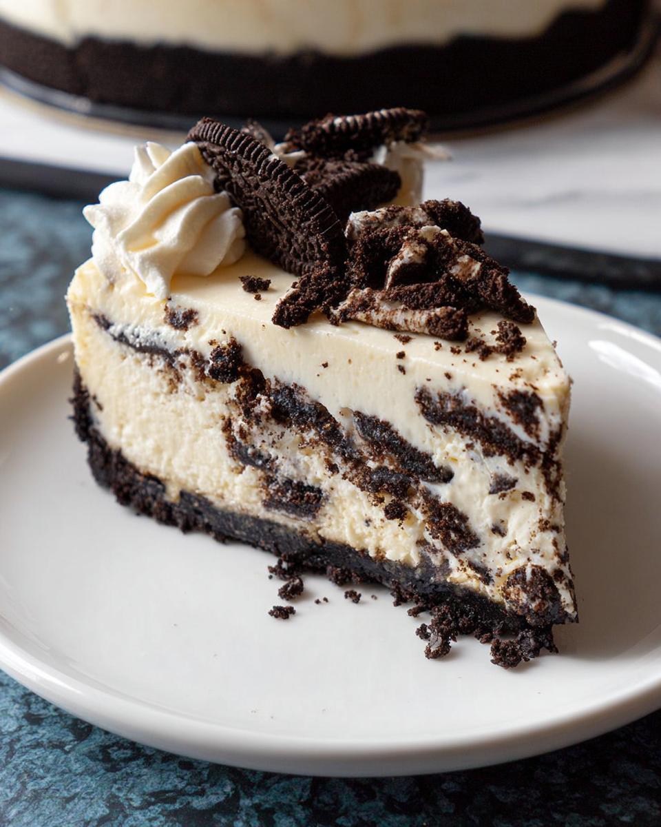 A perfect slice of Oreo Cookies and Cream Cheesecake topped with whipped cream and cookie pieces.