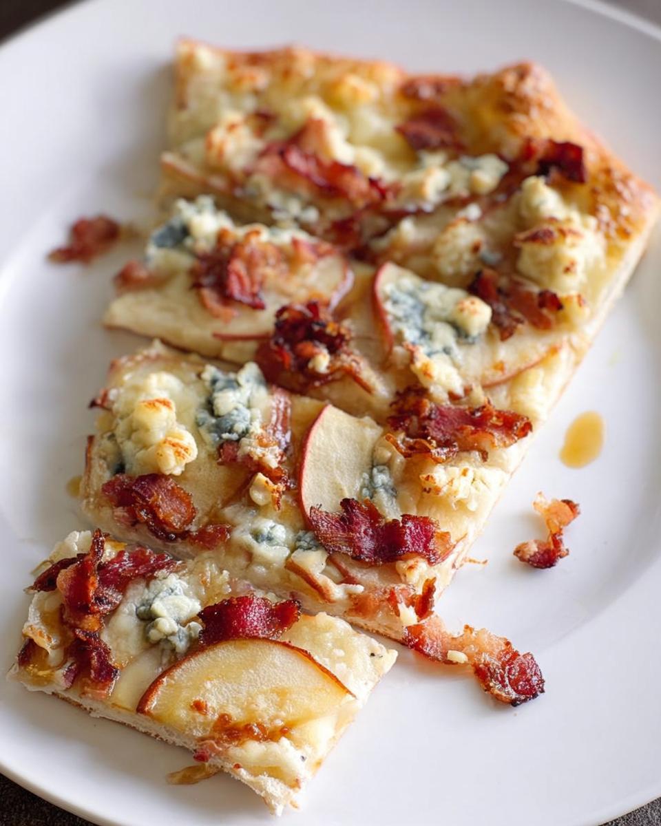Slices of 10-ingredient pizza topped with apple, bacon, and blue cheese on a white plate.