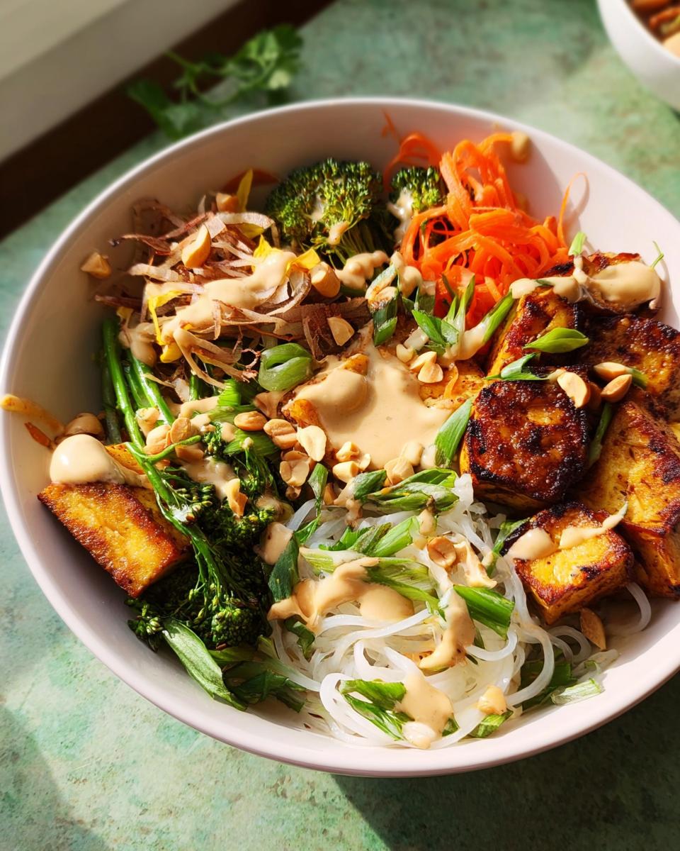 A vibrant and flavorful 20-Ingredient Rice Bowl with noodles, tofu, broccoli, carrots, and a creamy peanut sauce.