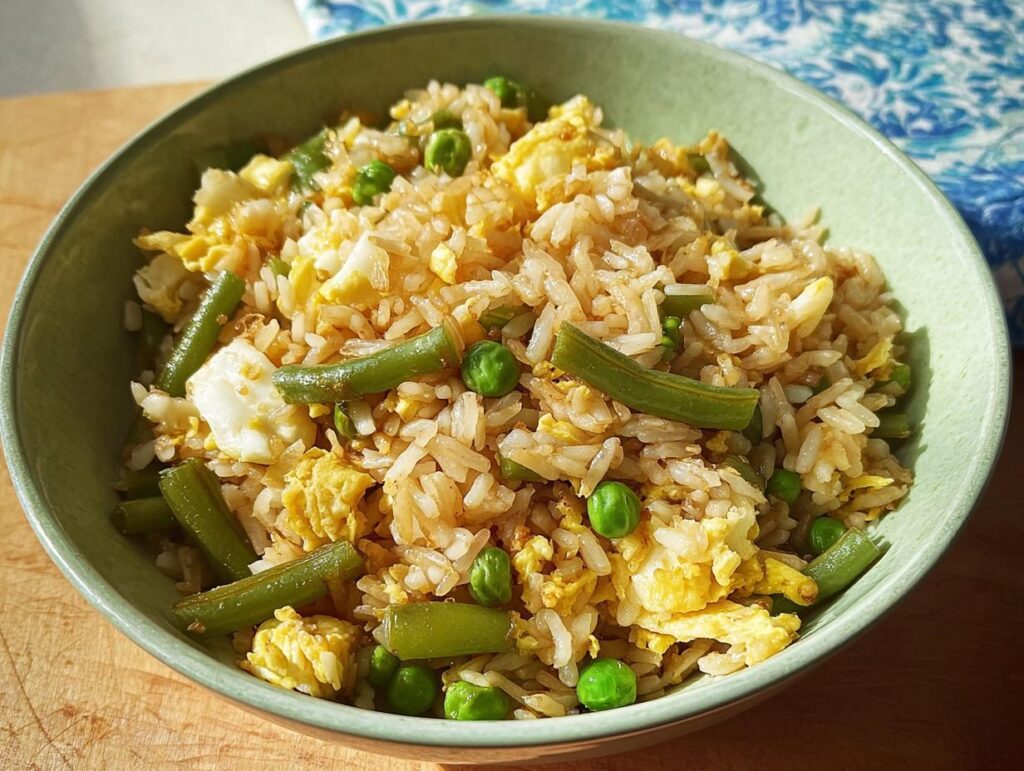 A bowl of 7-ingredient egg fried rice featuring scrambled eggs, peas, and green beans.