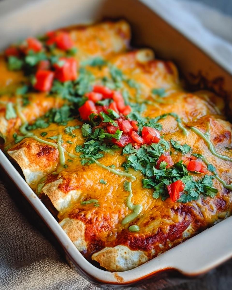 Close-up of baked chicken enchiladas topped with melted cheese, cilantro, diced tomatoes, and a drizzle of green sauce.