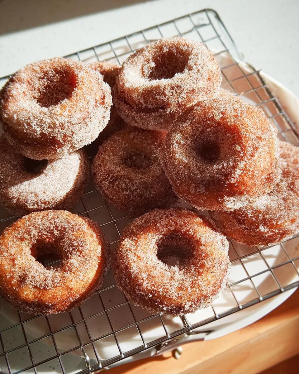 A pile of freshly made cinnamon sugar donuts on a cooling rack, perfect for breakfast ideas.
