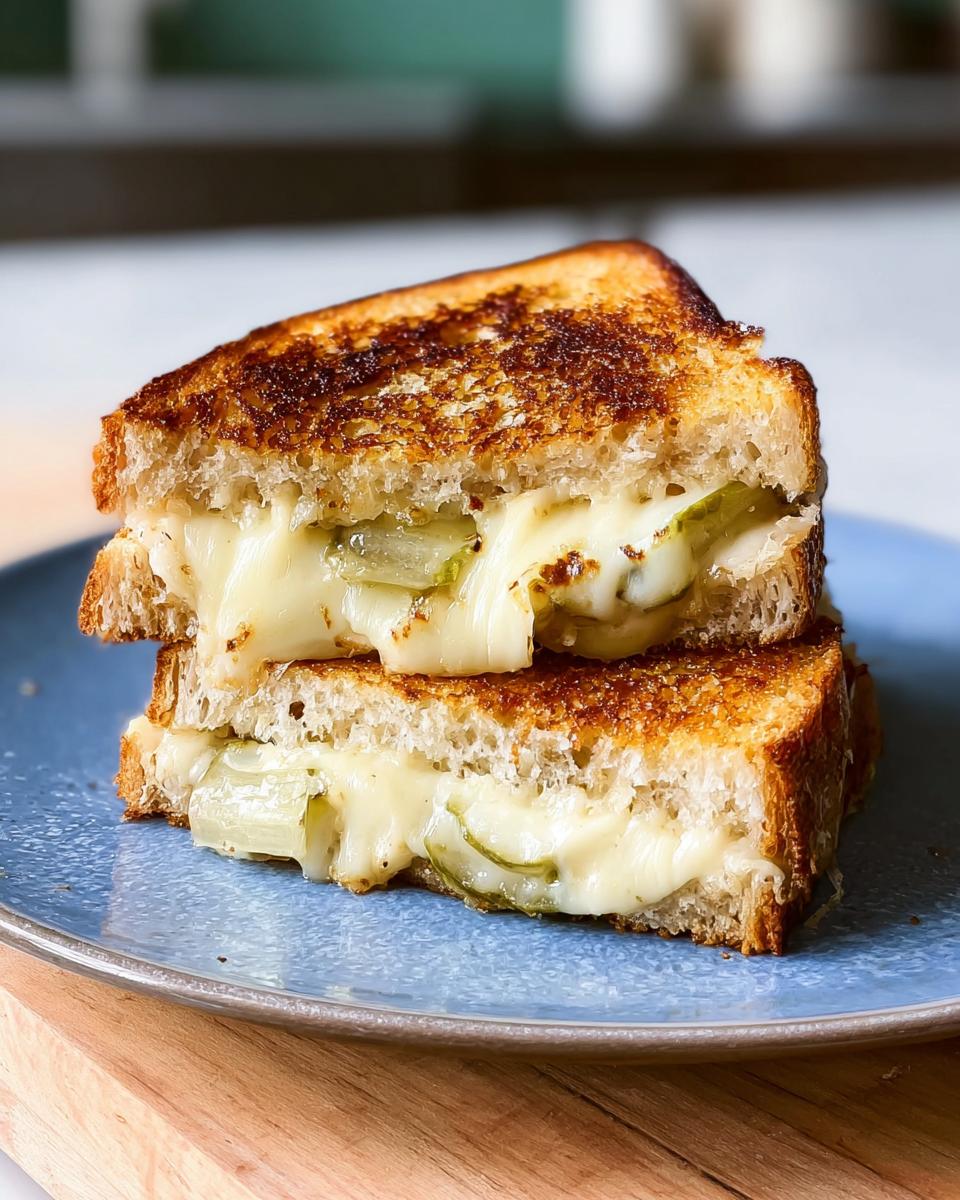 A close-up of a stacked grilled cheese sandwich with melted cheese and pickle slices, a perfect example of 20 Genius Grilled Cheese Recipes Ideas for Busy Weeknights.