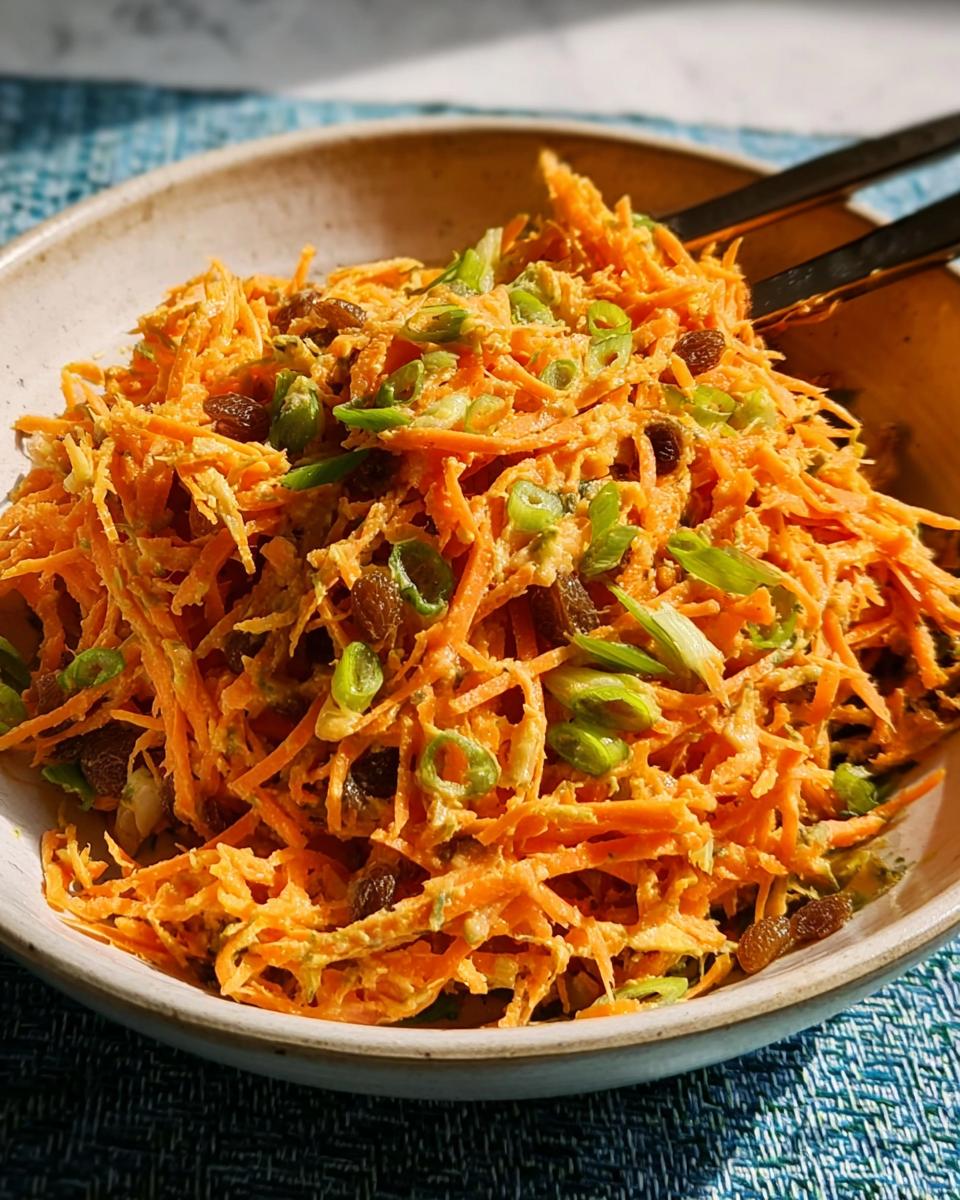 Close-up of a vibrant carrot salad with raisins and green onions, a perfect quick veggie side.