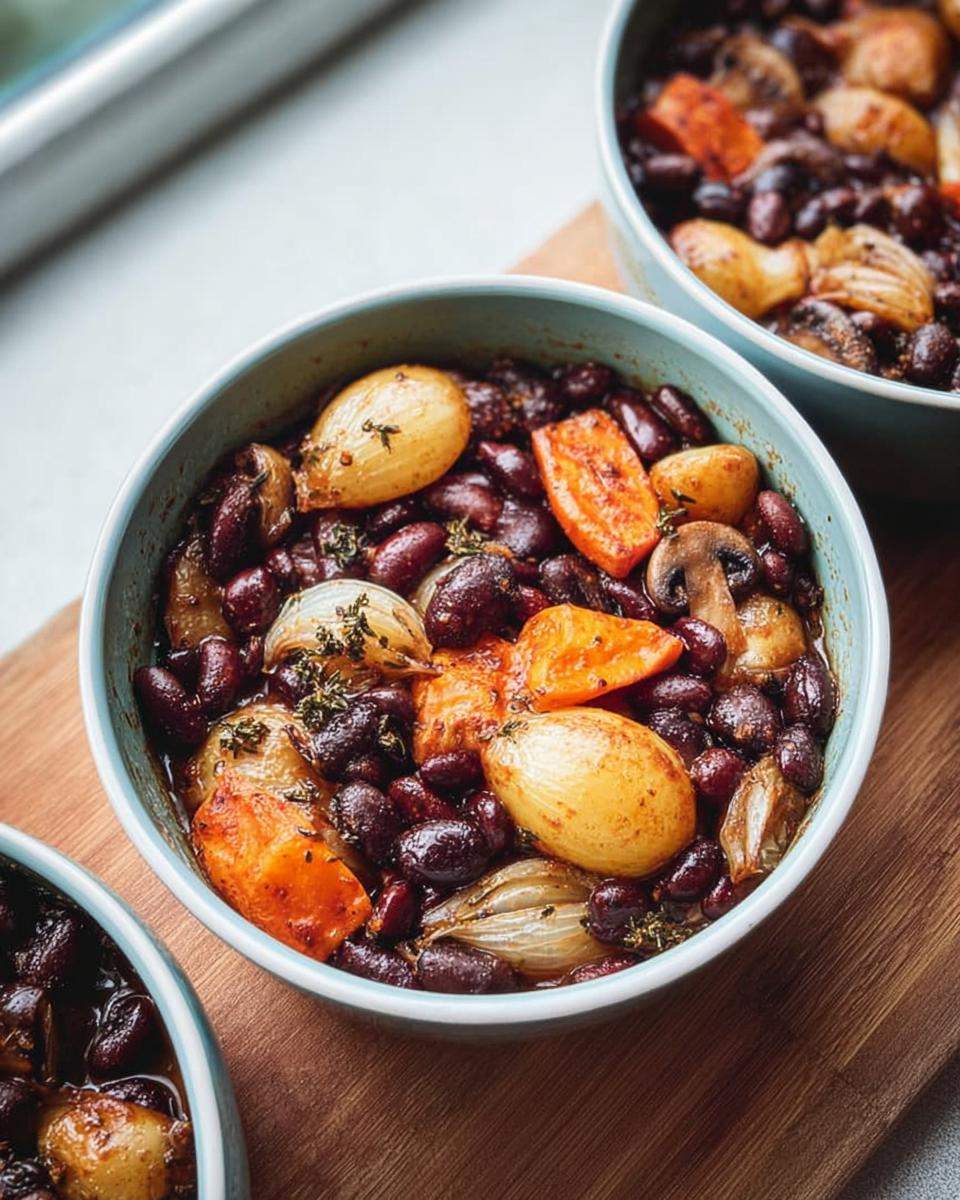Close-up of a bowl filled with a hearty veggie sides recipe featuring red beans, roasted onions, carrots, and mushrooms.