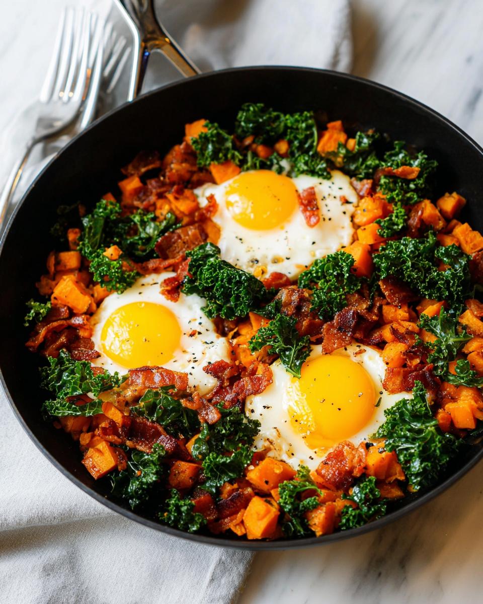 A skillet filled with a hearty BREAKFAST SWEET POTATO hash, topped with fried eggs, crispy bacon, and fresh kale.