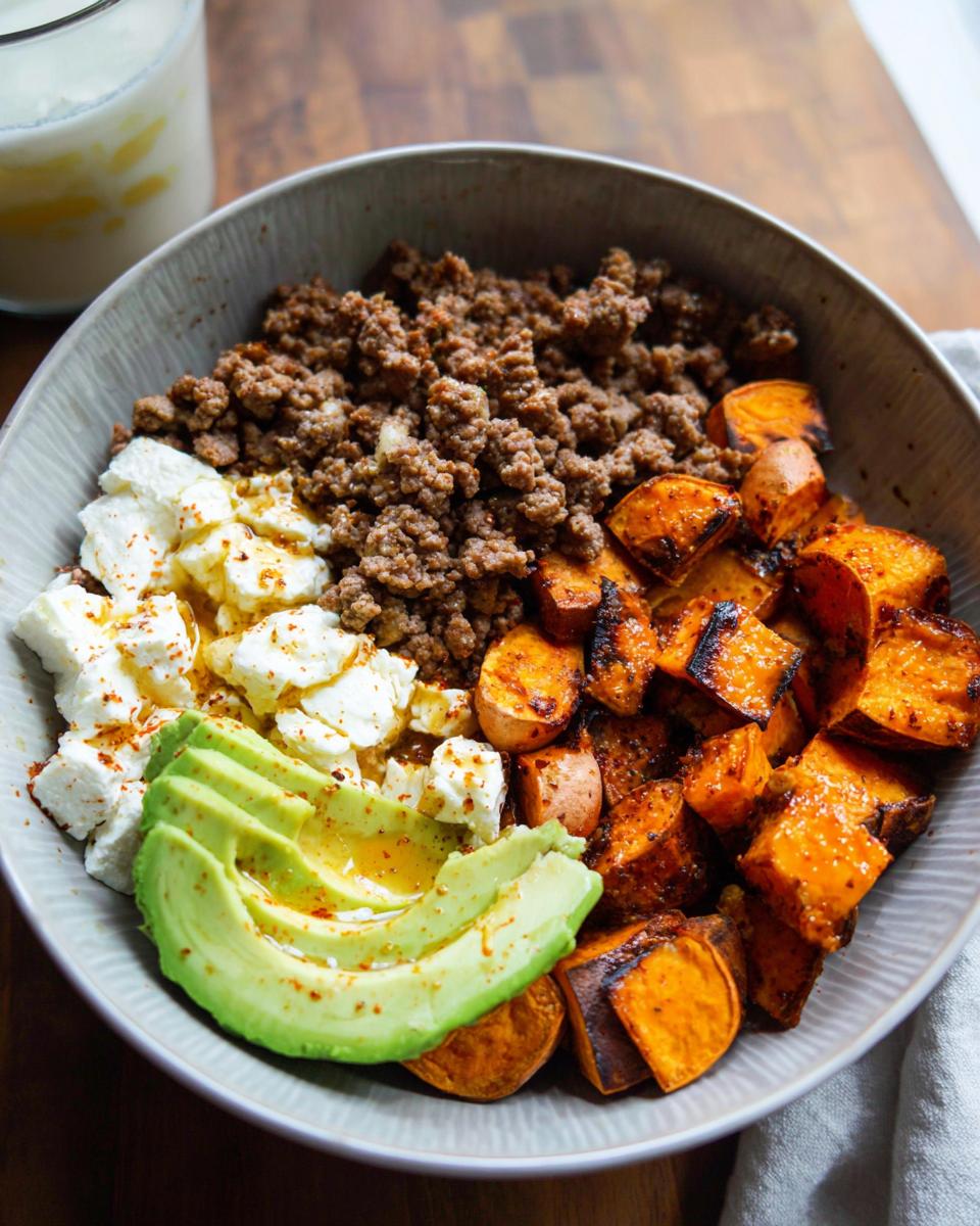 A delicious Ground Beef Hot Honey Bowl featuring seasoned ground beef, roasted sweet potatoes, crumbled feta cheese, and avocado slices.