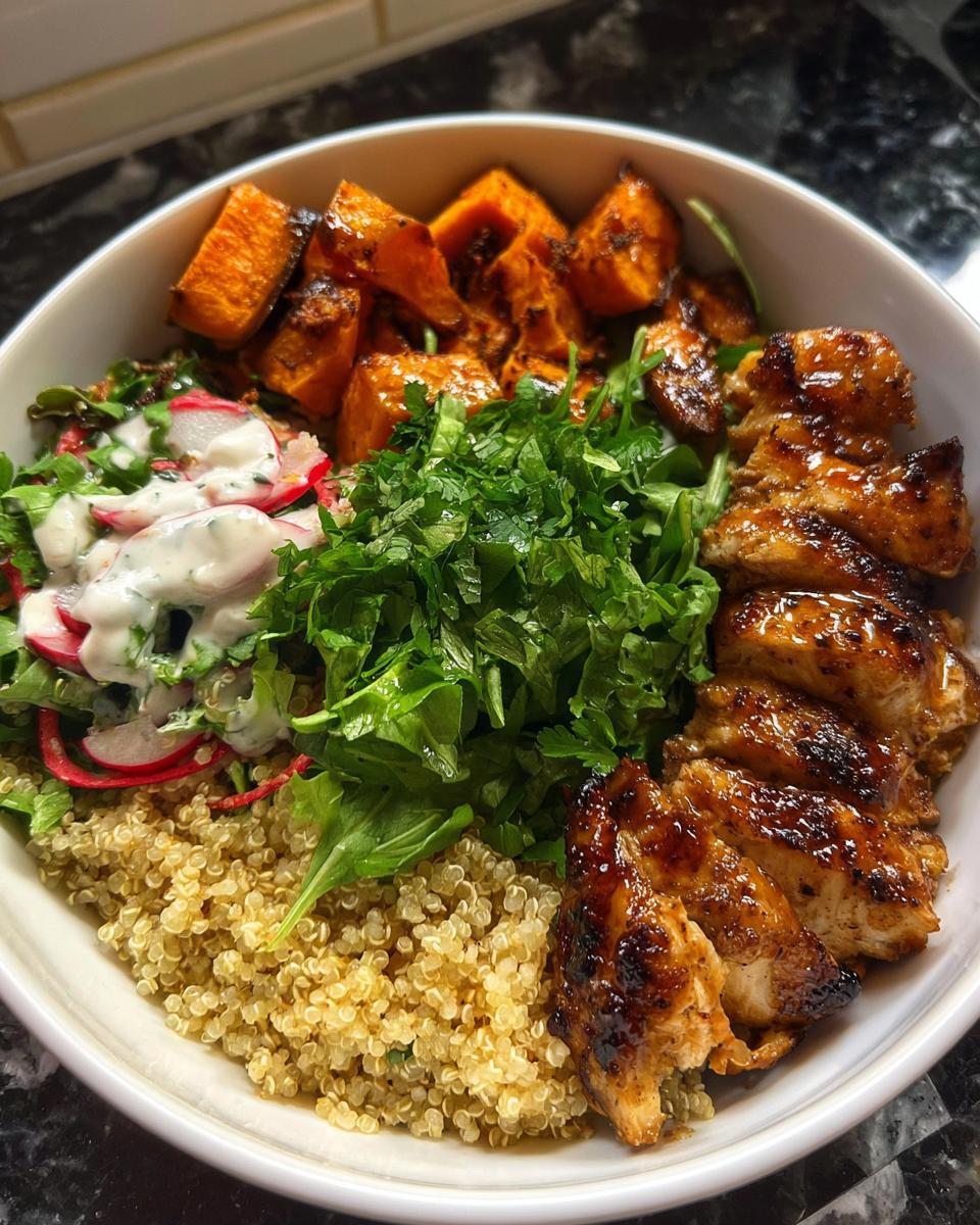 A delicious Hot Honey Chicken Bowl featuring grilled chicken, roasted sweet potatoes, quinoa, and a fresh salad.