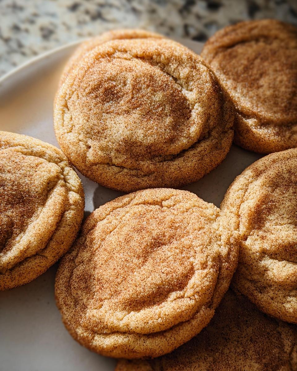 Close-up of several Chewy Churro Cookies dusted with cinnamon sugar on a plate.