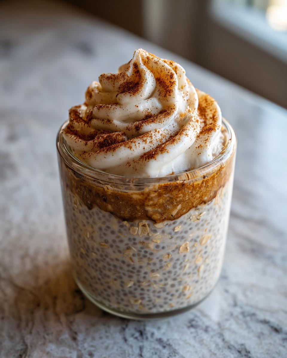 Overnight oats with cinnamon roll flavor, topped with whipped cream and cinnamon.
