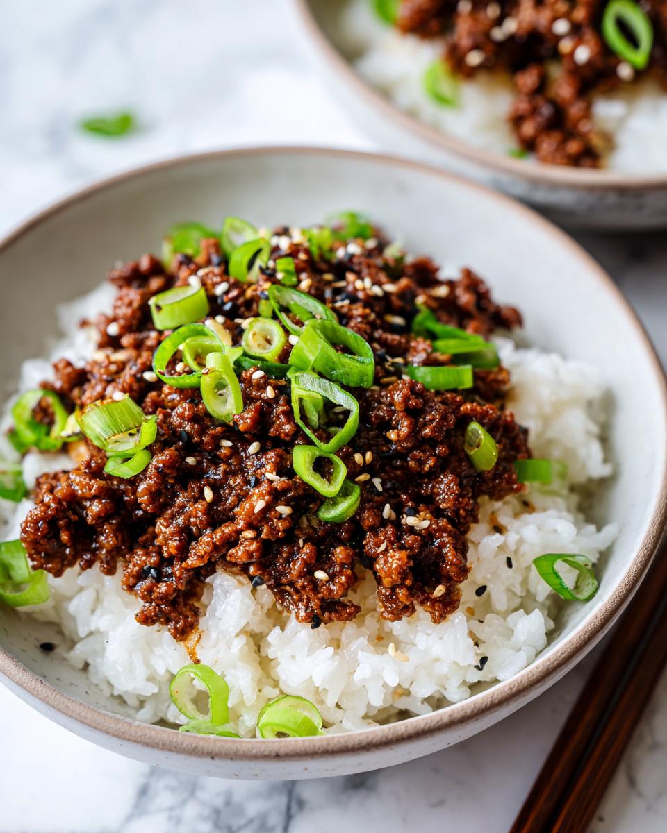 Close-up of a Korean beef rice bowl topped with ground beef, green onions, and sesame seeds.