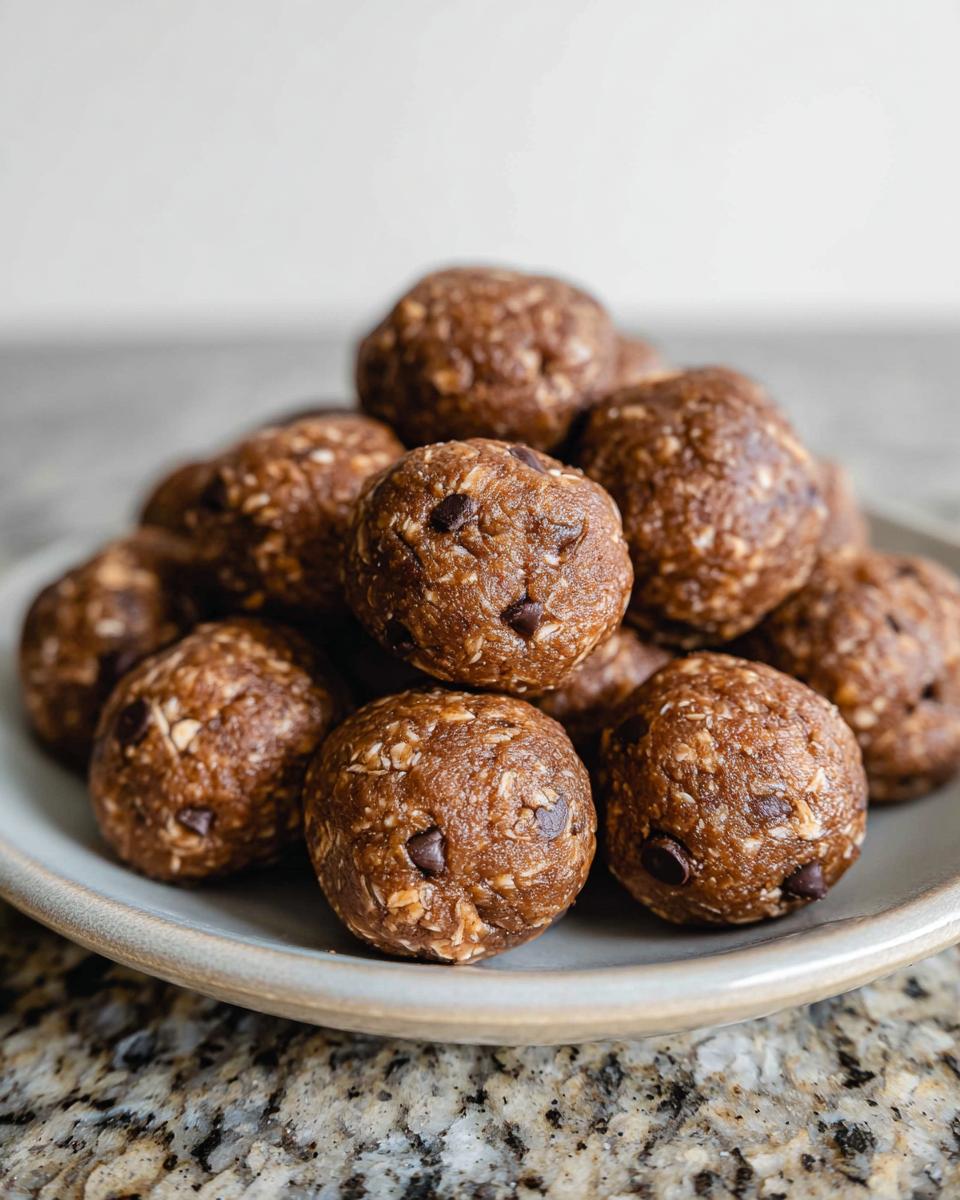 A pile of delicious No-Bake Chocolate Peanut Butter Protein Balls with visible chocolate chips and oats.